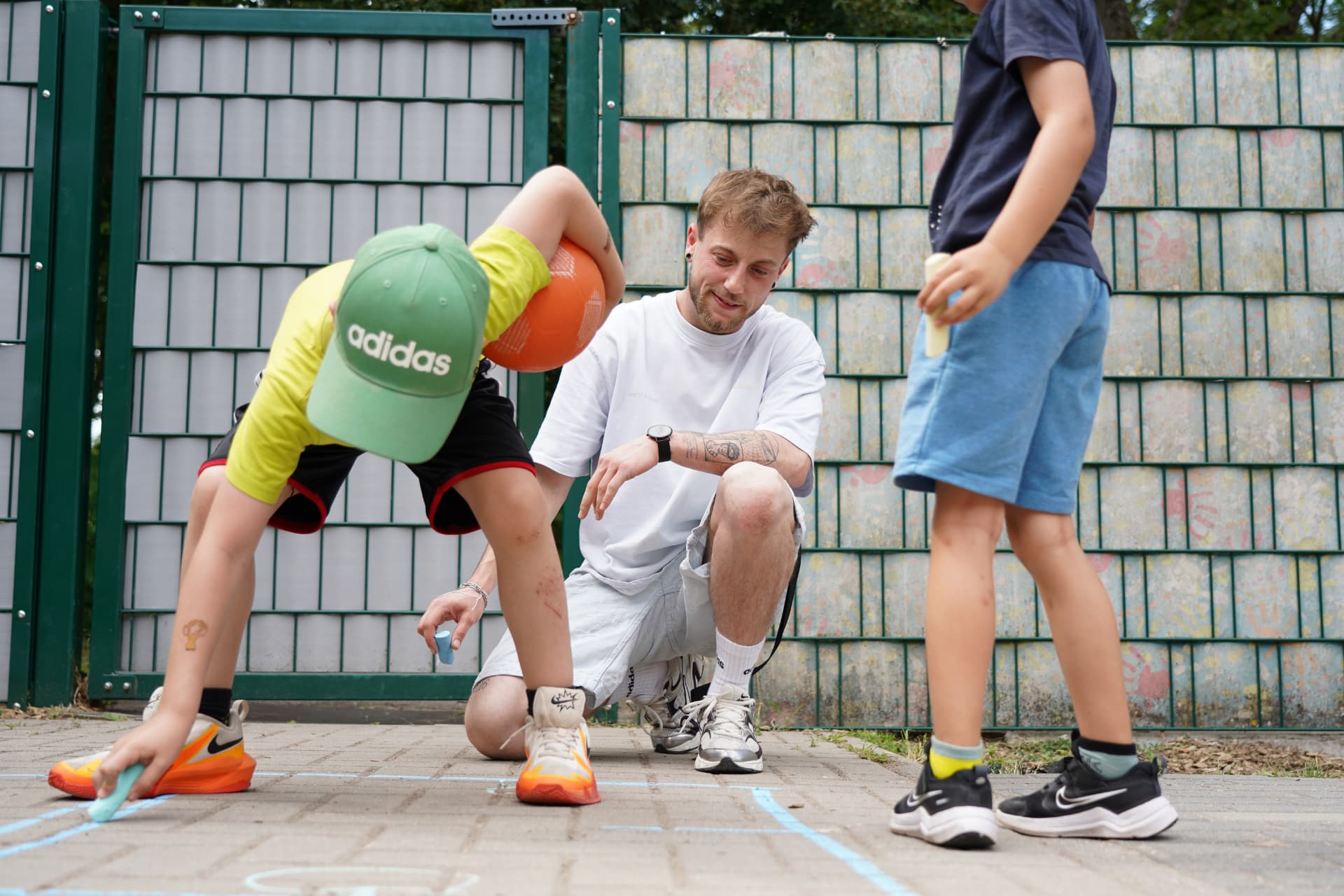 Erzieher der Gemeinde Brühl beim gemeinsamen Spiel mit Kindern auf einem Außenplatz