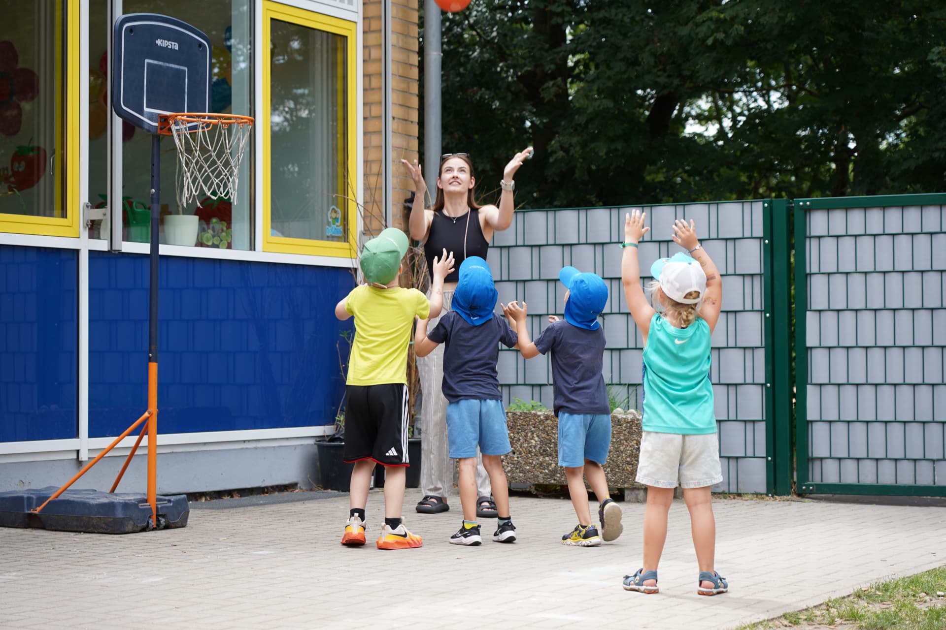Erzieherin der Gemeinde Brühl beim Basketballspiel mit Kindern auf einem Außenplatz